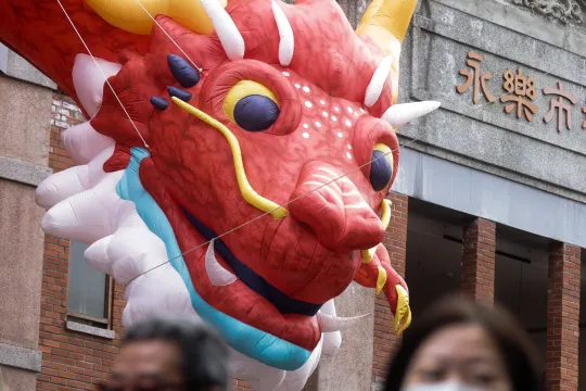 An inflatable dragon hangs on the wall of Yongle Market as people purchase goods for the Lunar New Year in Taipei on February 4, 2024. I-Hwa CHENG / AFP