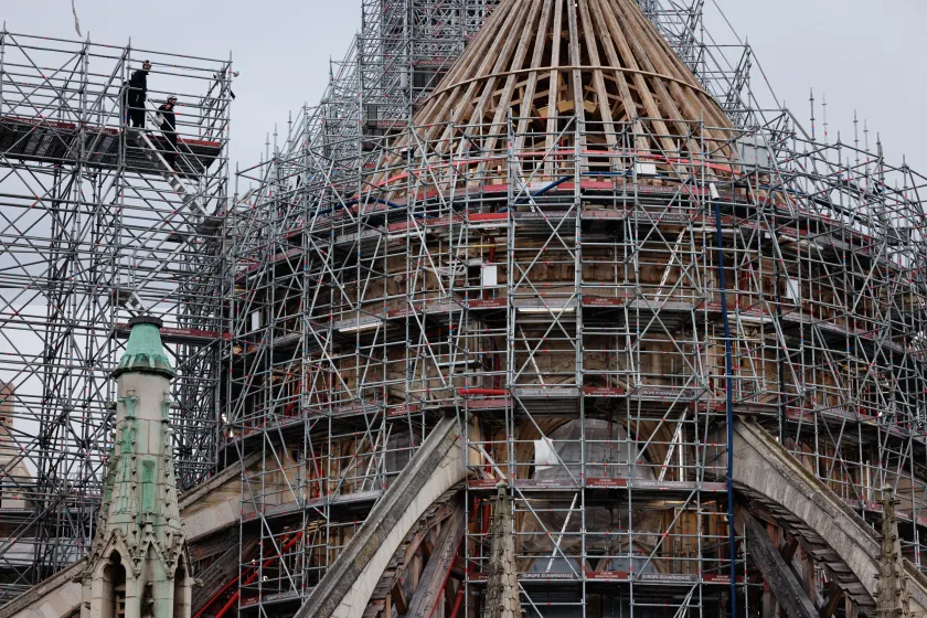 Workers operate on scaffoldings, during reconstruction work, around the wooden structure of the new spire in place at Notre-Dame de Paris Cathedral, on the Ile-de-la-Cite in Paris, on January 23, 2024. This spire is being reconstructed to be identical to the original one, destroyed in the fire of April 15, 2019 with the Cathedral set to be reopened at the end of 2024 according to the French Minsitry of Culture. JOEL SAGET / AFP